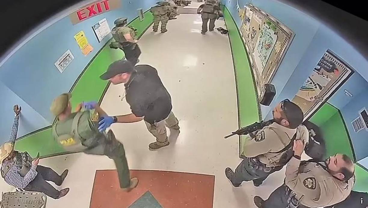 En la siguiente hora se ve a la policía agachada al final del pasillo mientras llegan refuerzos, que incluían oficiales con armas semiautomáticas y escudos antibalas.