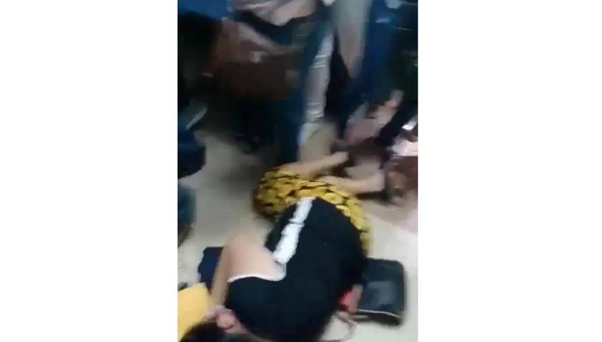 En medio del desorden, una dama fue derribaba por otras personas.