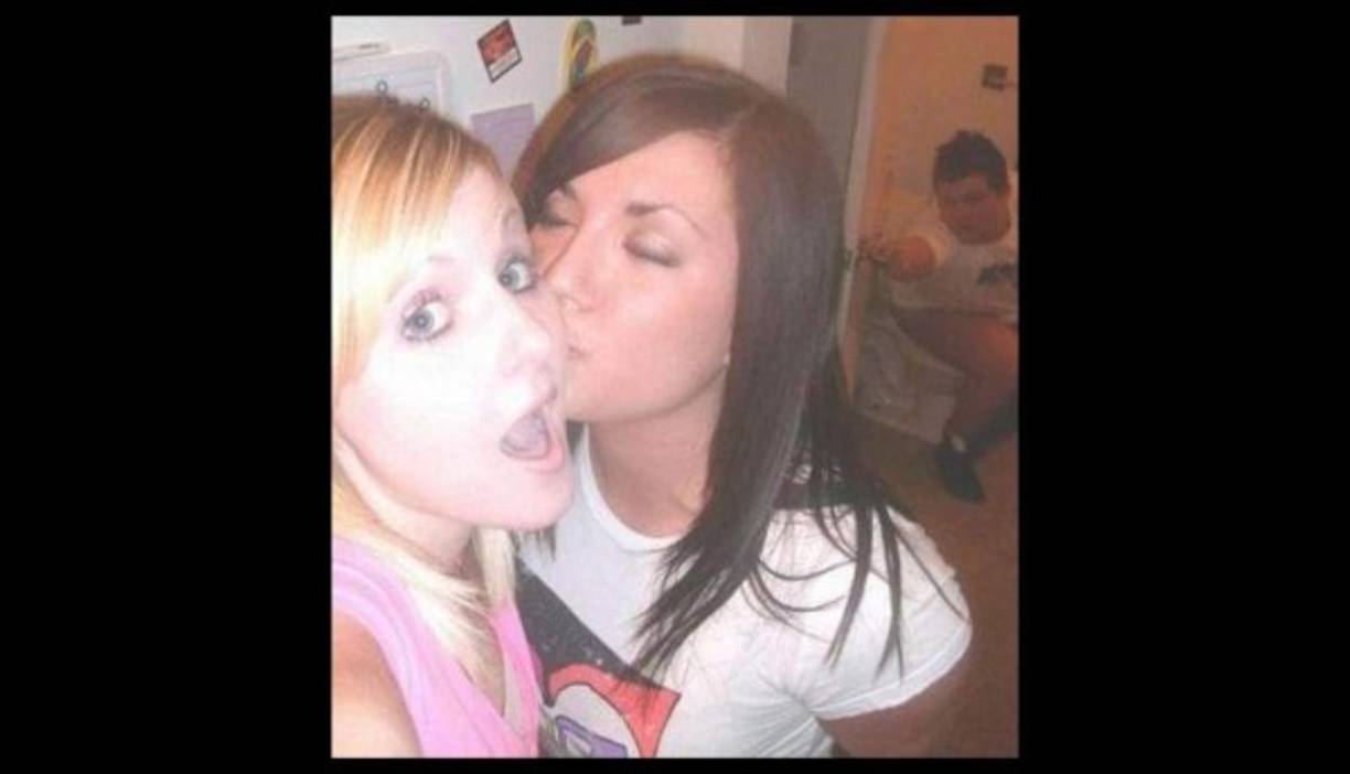 Estas dos jovencitas se toman una selfie mientras a sus espaldas, un joven intenta cerrar la puerta del baño.