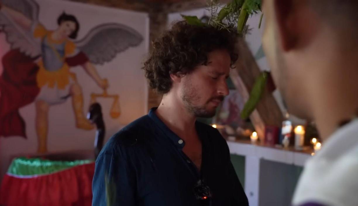 El influencer inicia en el video mostrando un sitio oscuro donde se practica la brujería y muestra como una sandalia es colgada en un árbol como símbolo para desearle la muerte a alguien y otros artículos en deterioro como amarres amorosos.