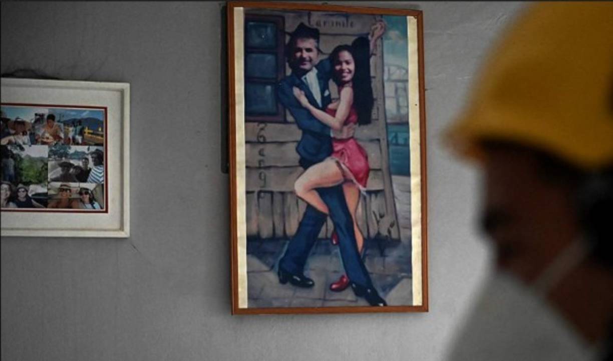 Un bombero investiga las causas del incendio provocado en la casa del ciudadano italiano Giorgio Scanu, visto en la foto de fondo, en el municipio de Santa Ana de Yusguare en Choluteca. AFP