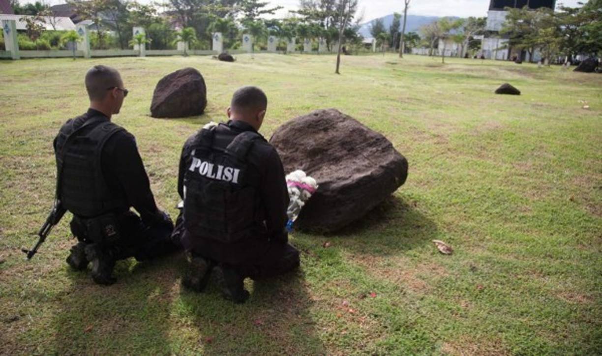 Policías rezan por sus amigos y parientes muertos en una fosa común de víctimas del 26 de diciembre 2004 tsunami en Banda Aceh.