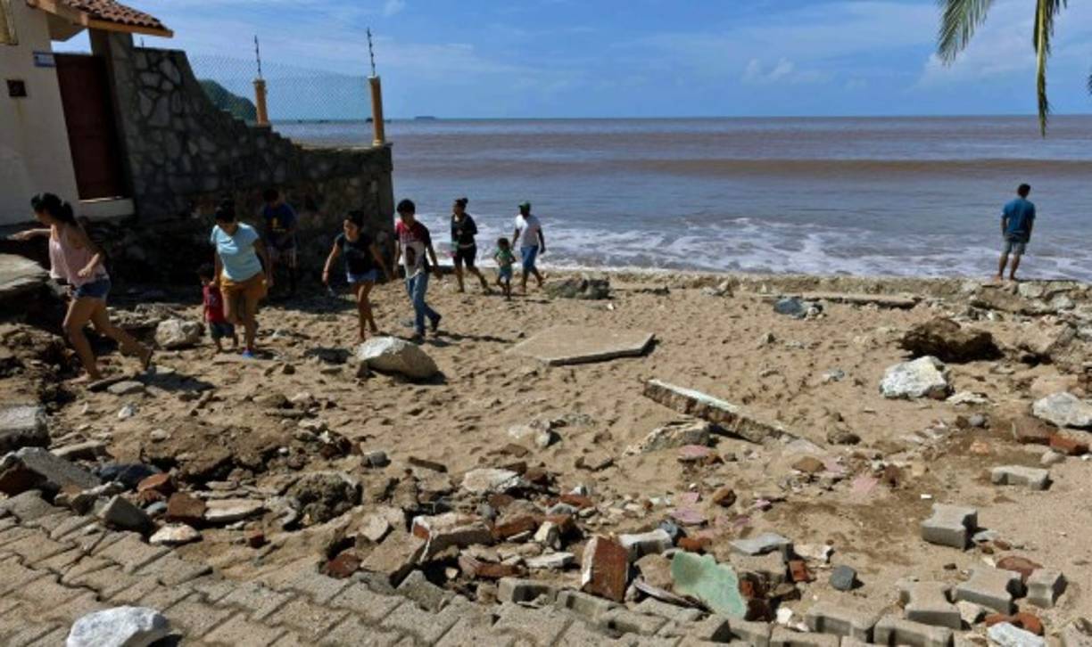 Pobladores caminan sobre los escombros que han dejado el huracán Patricia en una de las principales playas de Jalisco.