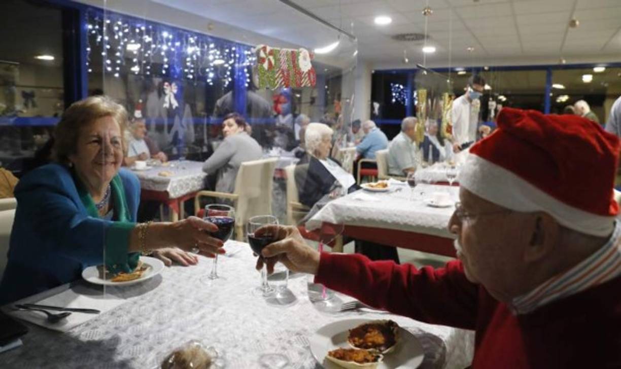 En España, adultos mayores residentes del centro Domus VI San Lázaro celebran de forma amena y sin mascarilla durante la cena de Nochebuena con un menú especial y en mesas con mamparas.