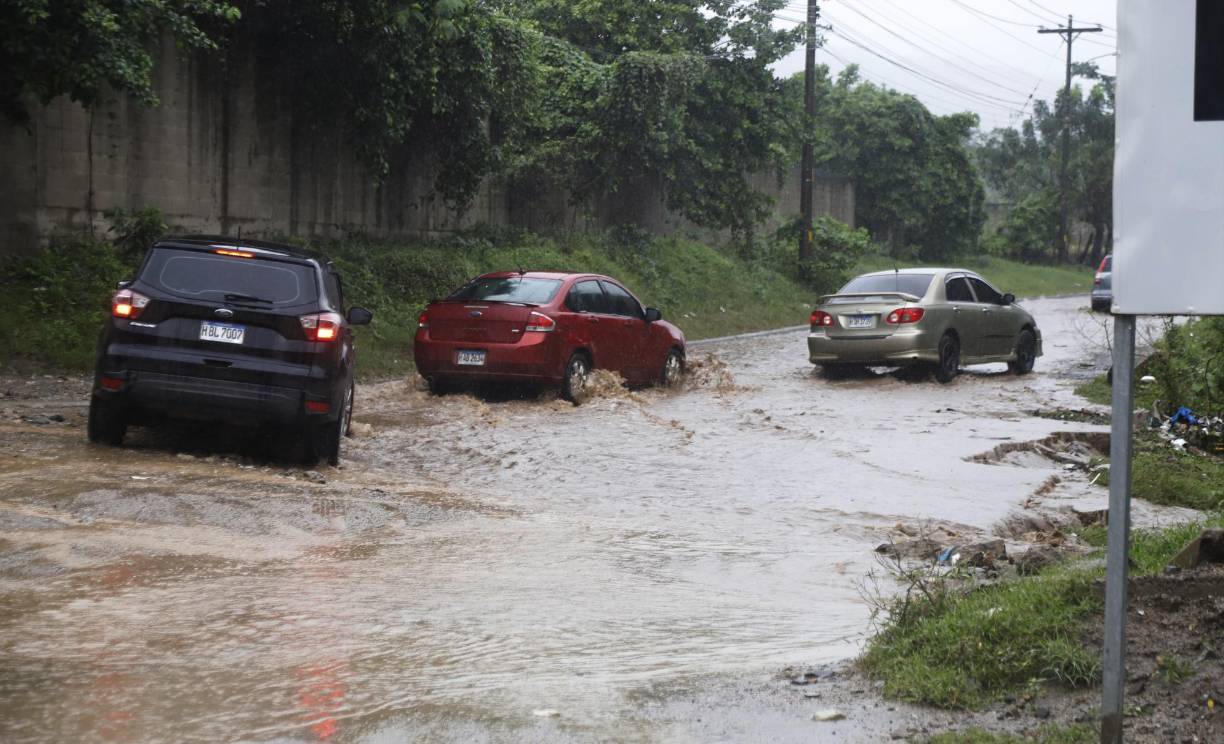 Conductores realizan maniobras para poder pasar sobre una quebrada desbordada en la entrada a Chamelecón.
