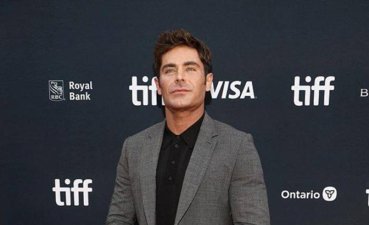 Después de compartir información sobre su nueva apariencia, Zac se veía elegante con un traje a cuadros gris pálido y una camisa negra cuando llegó al estreno.