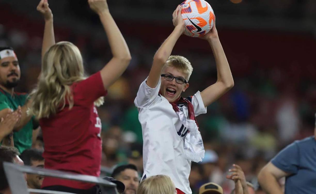 Un niño estadounidense, alegre tras quedarse con un balón en las gradas del estadio.