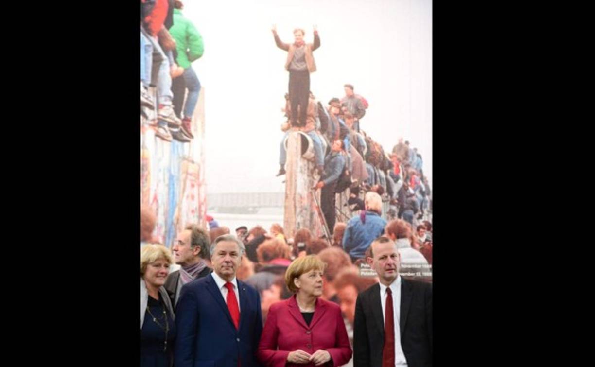 El alcalde de Berlin, Klaus Wowereit, La Canciller Angela Merkel y Axel Klausmeier en pie frente a una reprodución del muro de Berlín en 1989.