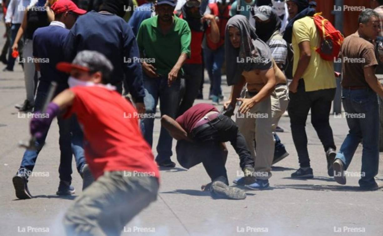 Jóvenes encapuchados respondieron a los policías con piedras y regresando las bombas lacrimógenas.
