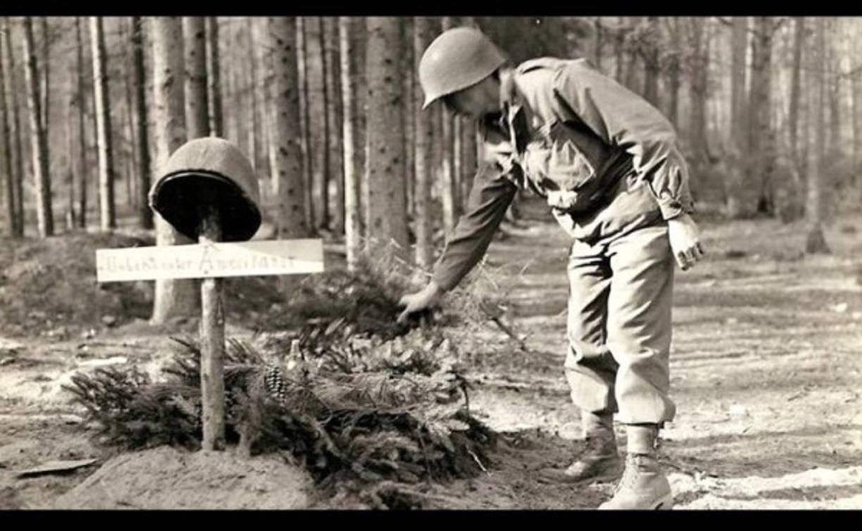 Un soldado estadounidense deposita flores sobre una tumba improvisada y sin identificar. <br/>