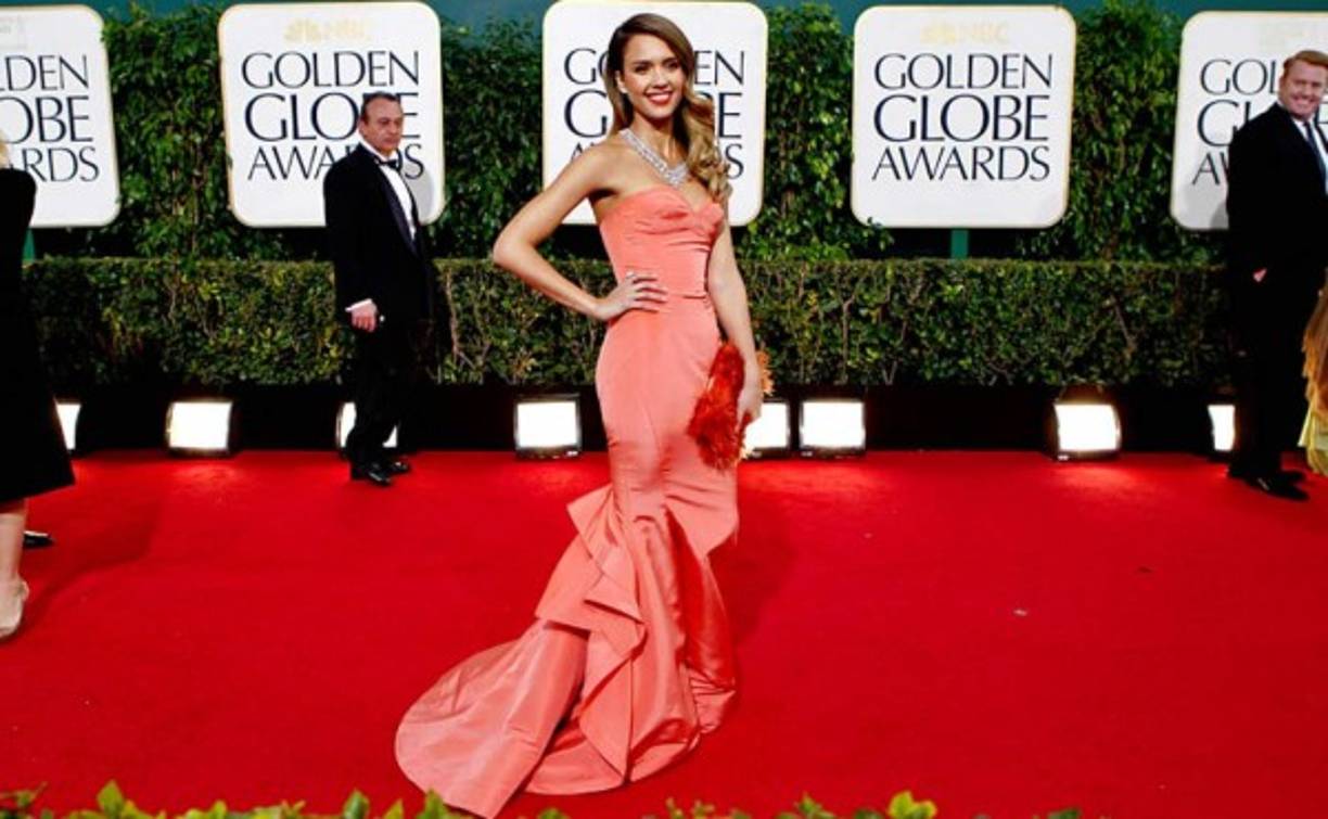 Jessica Alba con un vestido ajustado rematado con volantes en color coral, divina en los Globos de Oro 2013.