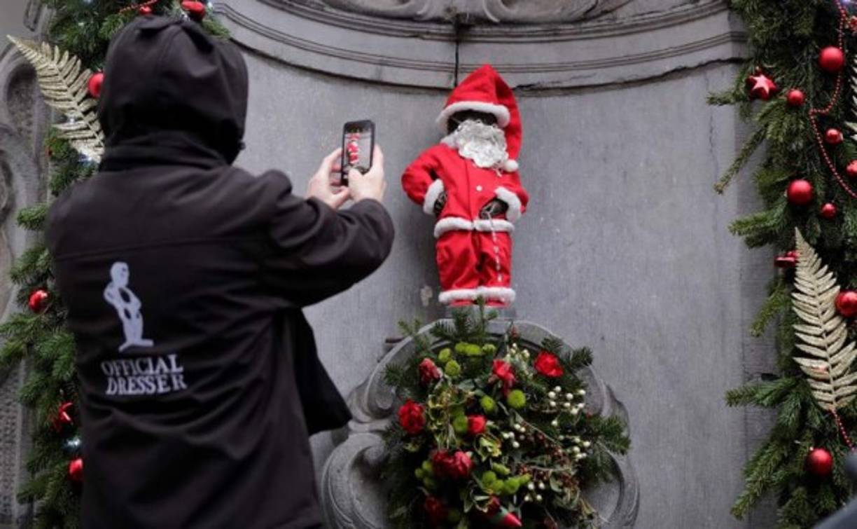En Bruselas, Bélgica, un solitario hombre toma una fotografía a una escultura con traje de Papá Noel, que forma parte de los arreglos navideños que la capital belga hizo a sus ciudadanos.