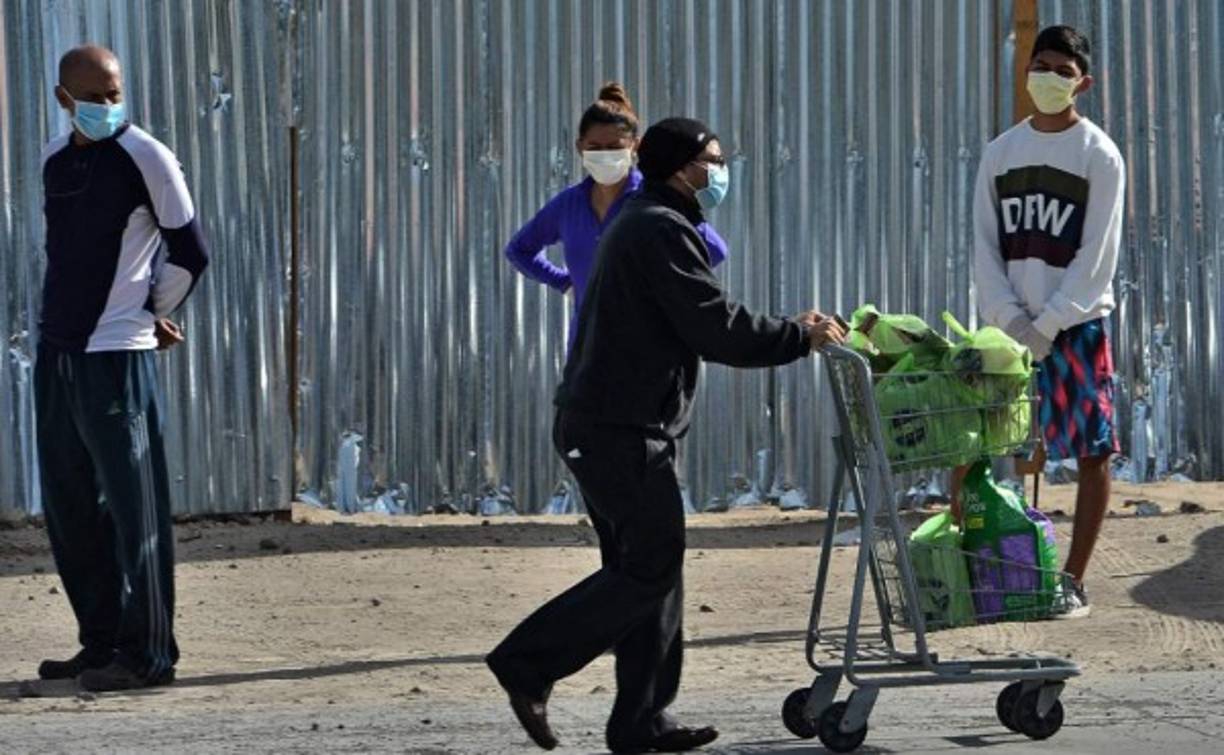 Un hombre se va después de comprar víveres mientras otros clientes hacen cola a una distancia de un metro entre otros. Las autoridades vigilaron en Tegucigalpa, La Ceiba y Choluteca que las medidas se respetaran.