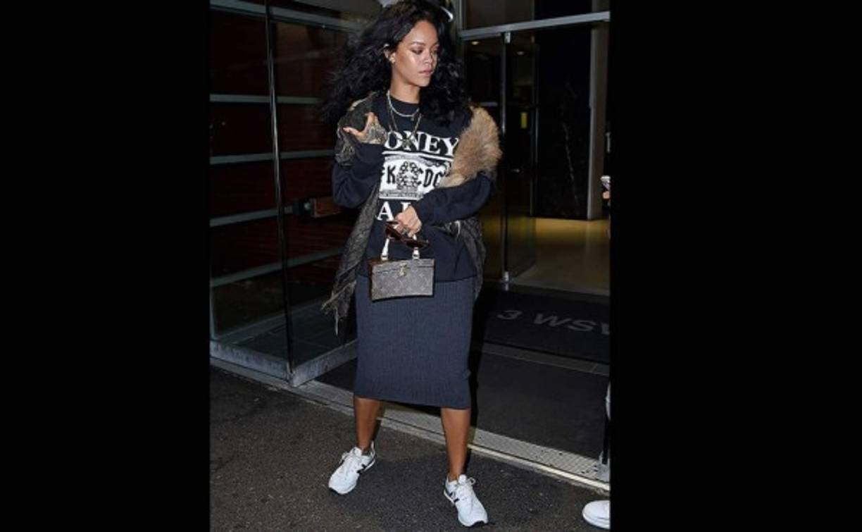RIHANNA. Vimos a la cantante paseando por Nueva York con una falda gris por debajo de la rodilla, camiseta estampada en blanco y negro y un abrigo con ribete de pelo que conjuntó con zapatillas deportivas New Balance y un bolsito cofre de Louis Vuitton.<br/><br/>