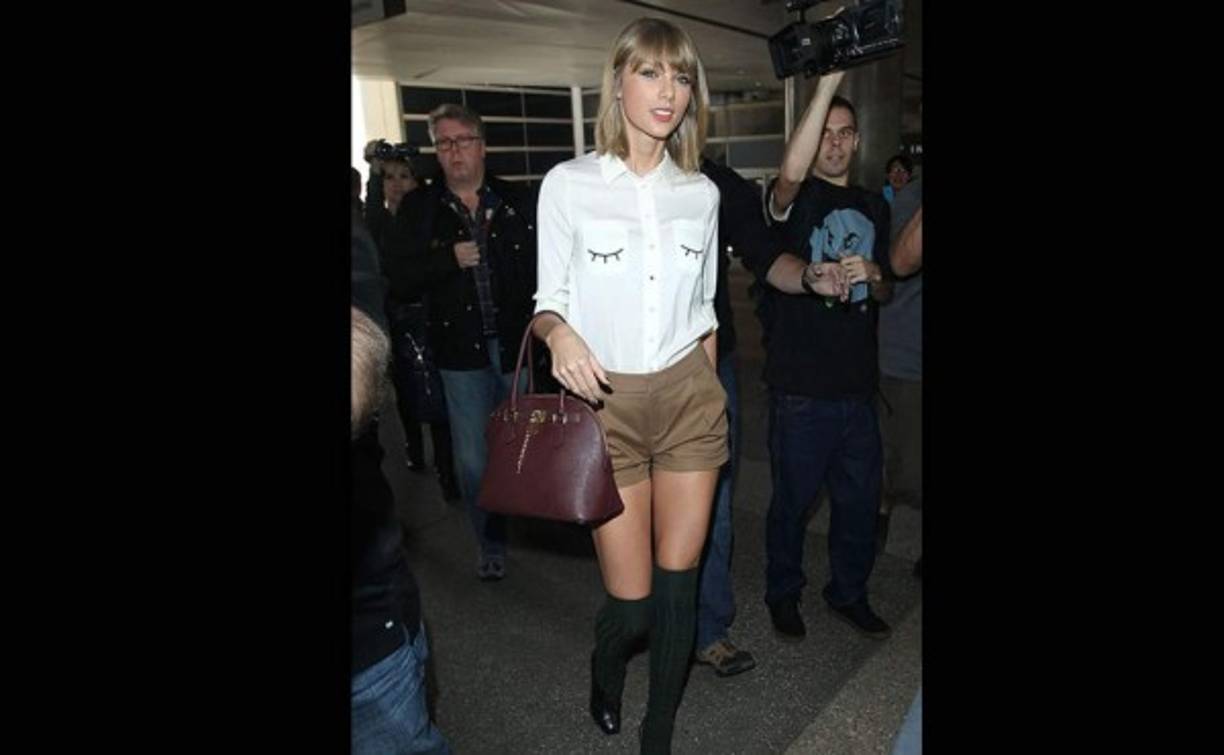 TAYLOR SWIFT. Con este coqueto conjunto de short marrón de Everlane y blusa blanca con dibujo de pestañas en los bolsillos de Miss Patina vimos a la cantante en el aeropuerto de Los Ángeles.