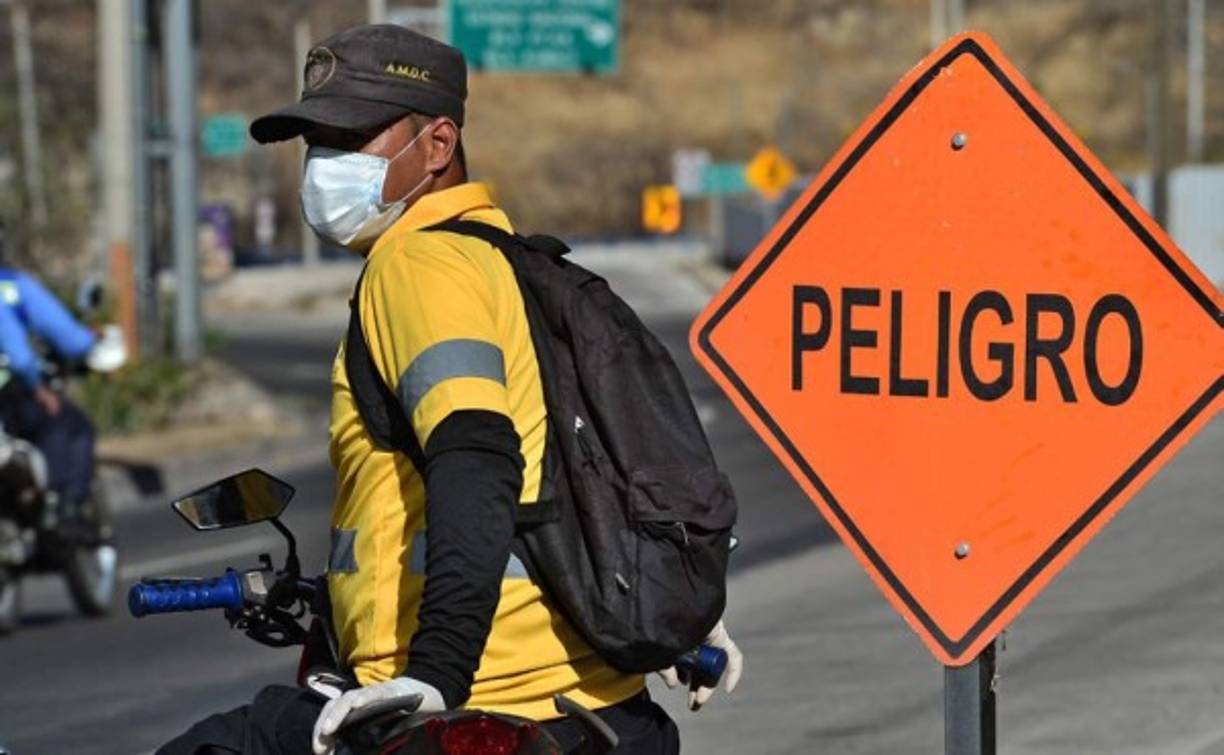 Un hombre usa una máscara facial y guantes mientras se prepara para conducir su motocicleta durante un descanso del toque de queda impuesto por el gobierno contra la propagación del nuevo coronavirus, en Tegucigalpa, el 19 de marzo de 2020.