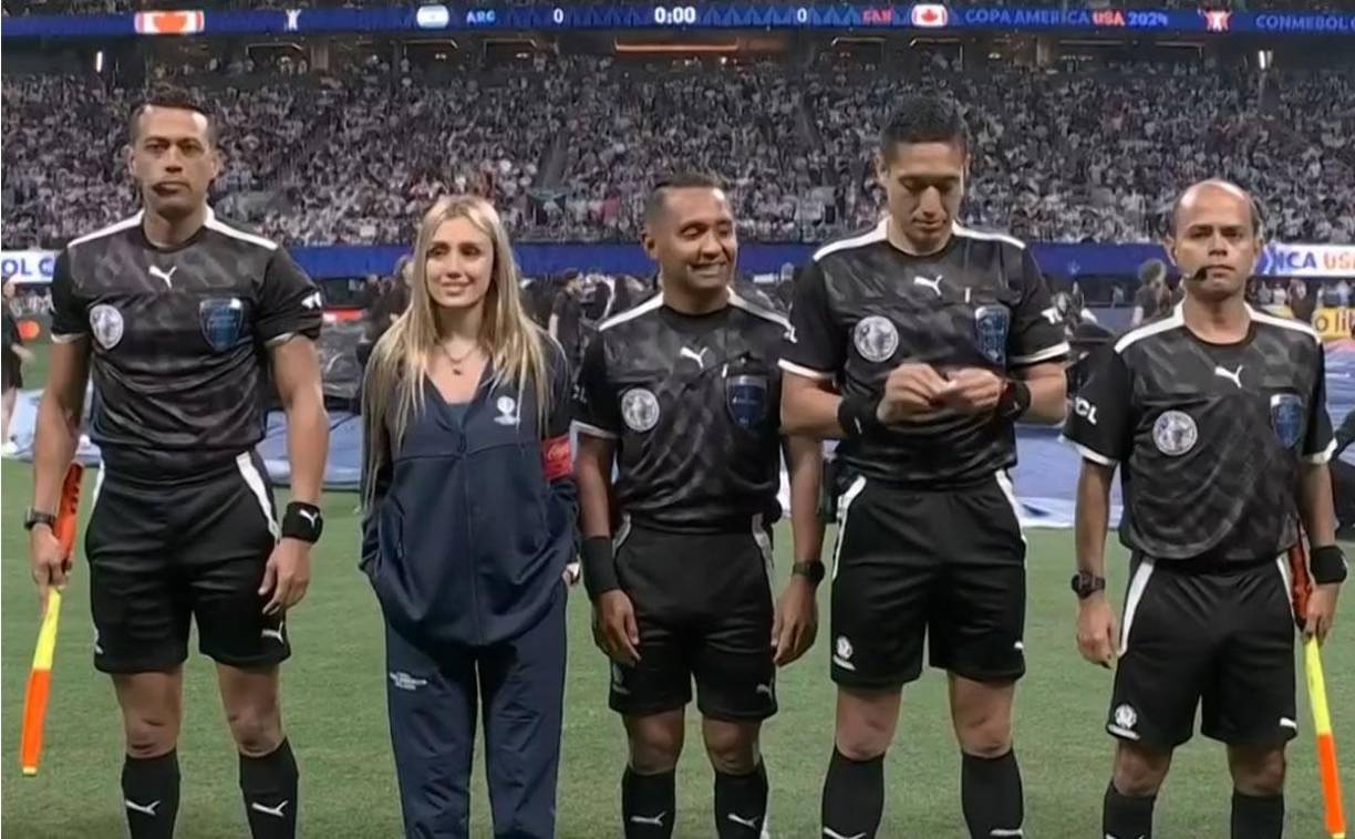 La periodista argentina Morena Beltrán sorprendió al aparecer junto a los árbitros, entre ellos Iván Barton, durante el sorteo de los capitanes de Argentina y Canadá. Messi la saludó con un beso. ¿Qué hacía la reportera ahí? Todo indica que se trata de una movida de marketing de alguna de las marcas que auspicia el evento.