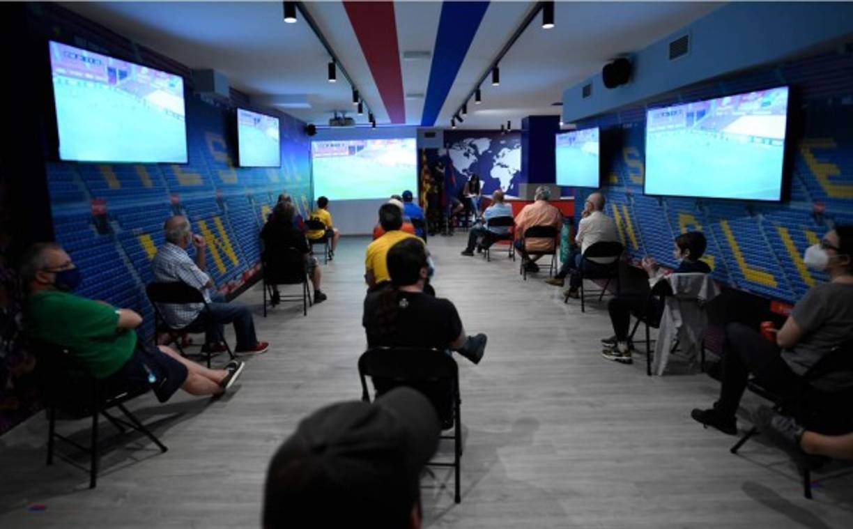 Aficionados del Barça con máscara facial miraron el partido contra el Mallorca en un club de fans en Barcelona.