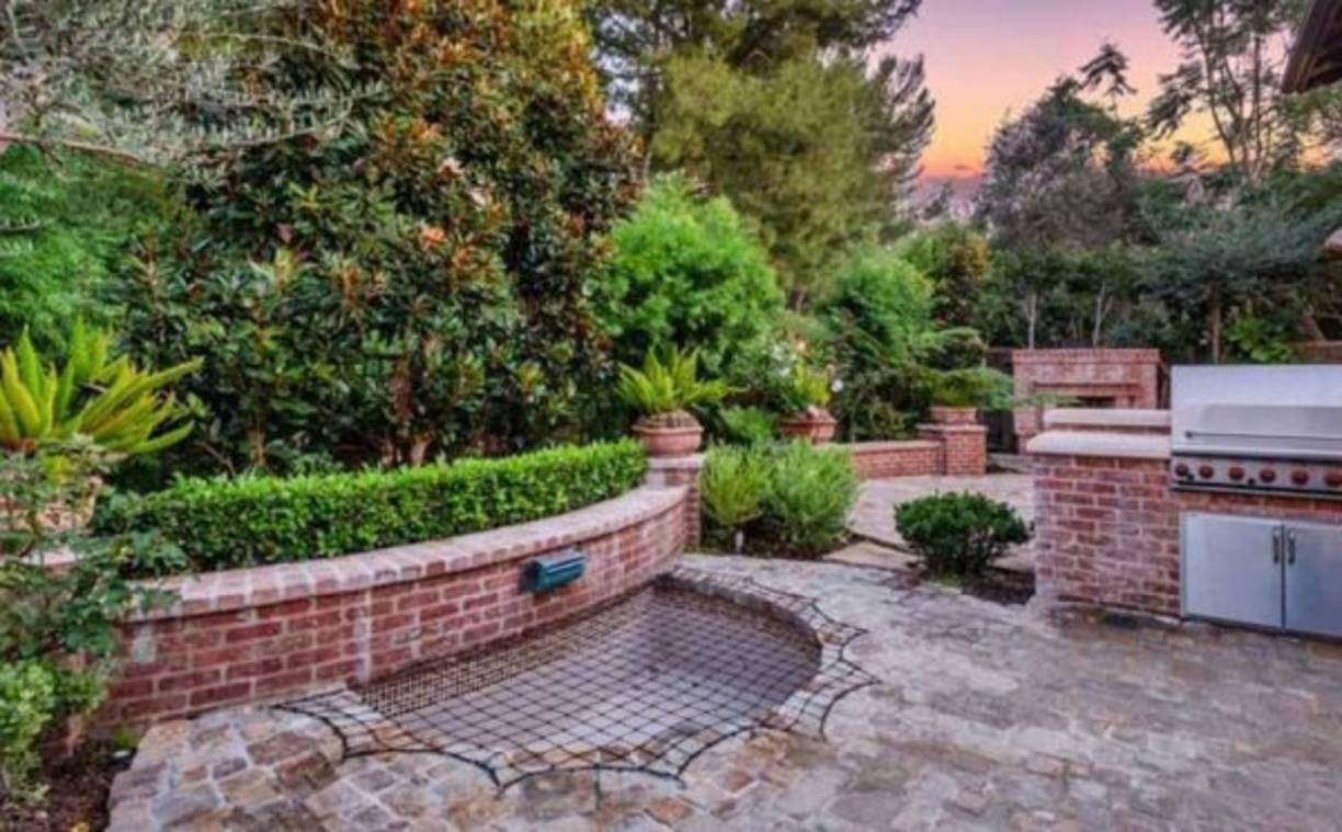 En la parte trasera de la casa se ubican algunas puertas de estilo francés, lo que da un toque rústico elegante a este espacio que se complementa con un patio de piedra. Cabe destacar que en este punto también se ubica una chimenea de ladrillos y un spa sobre el suelo.