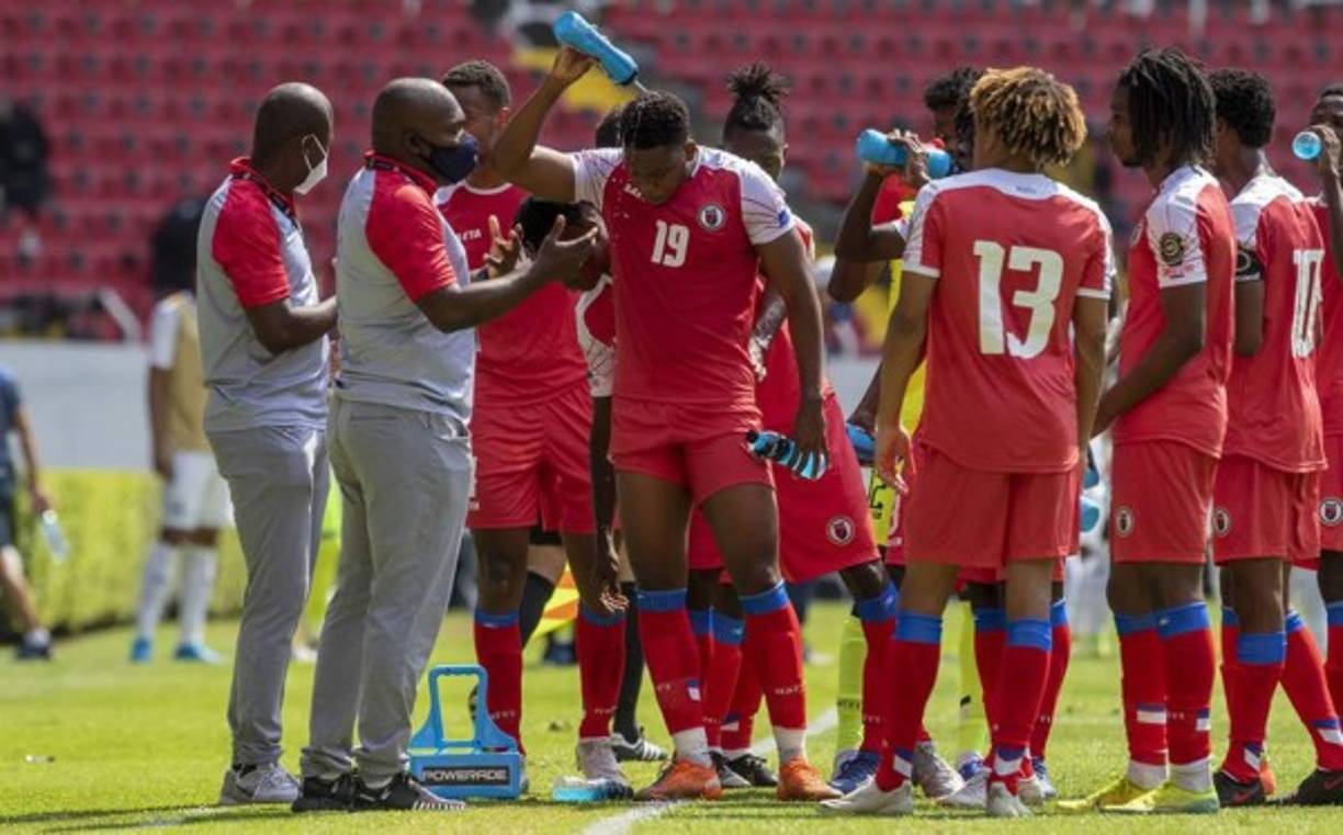 El entrenador de los haitianos Webens Prinsimé dando indicaciones a sus futbolistas durante una pausa para hidratación.