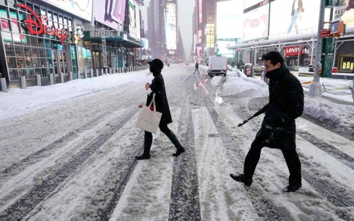 People cross the street in Times Square on December 17, 2020 in New York, the morning after a powerful winter storm hit the US northeastern states. - A major snowstorm hit the US east coast during Thursday's early hours, creating extra challenges in the midst of a coronavirus pandemic and a mass vaccination rollout taking place across the region.The winter storm, moving over New York, Pennsylvania and other northeastern states, leaves millions facing more than a foot of snow a week before Christmas, potentially disrupting coronavirus testing and delaying holiday deliveries. It also left more than 60 million people under bad weather warnings from Maine to South Carolina. (Photo by TIMOTHY A. CLARY / AFP)