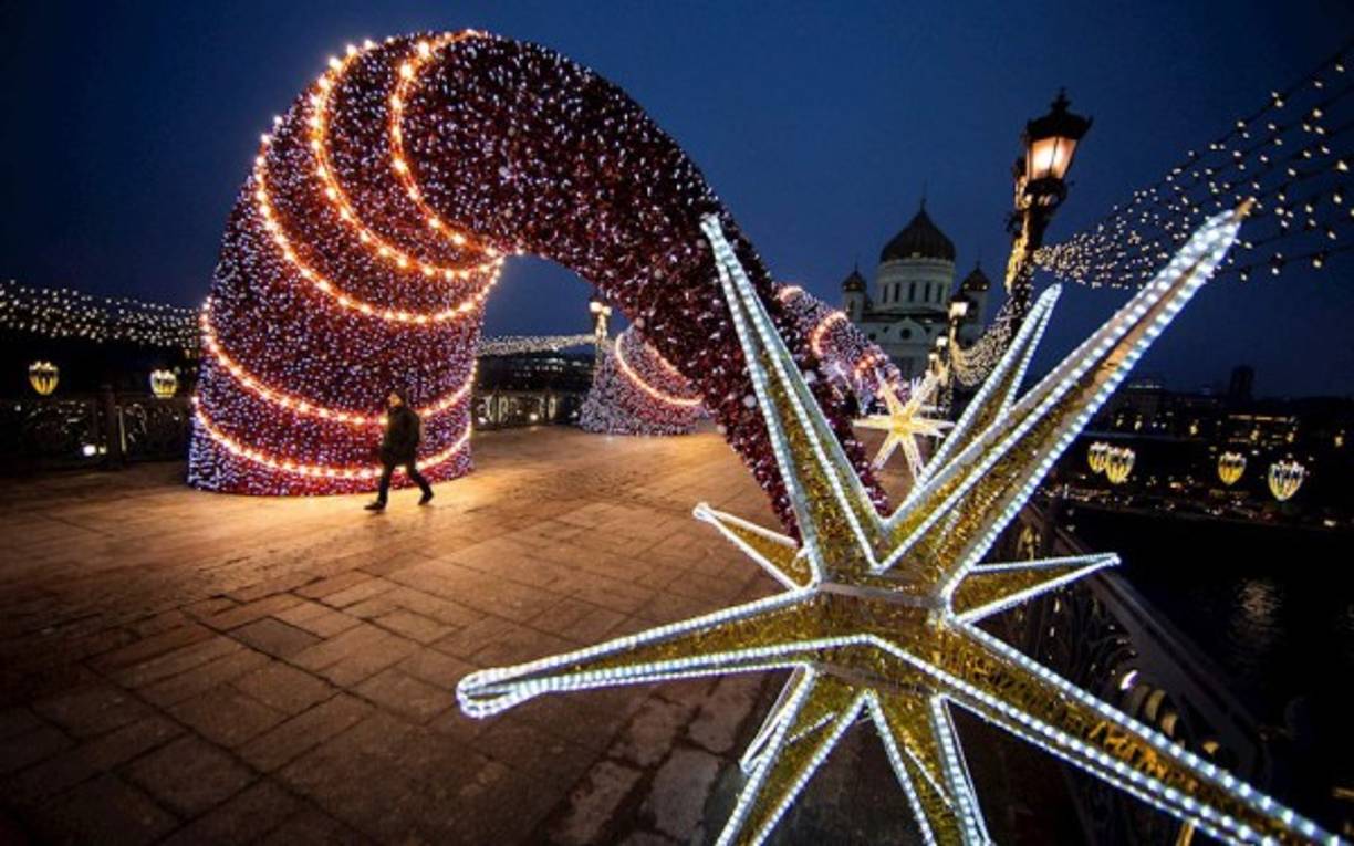 Un hombre camina a lo largo de un puente decorado frente a la Catedral de Cristo Salvador en Moscú, Rusia.