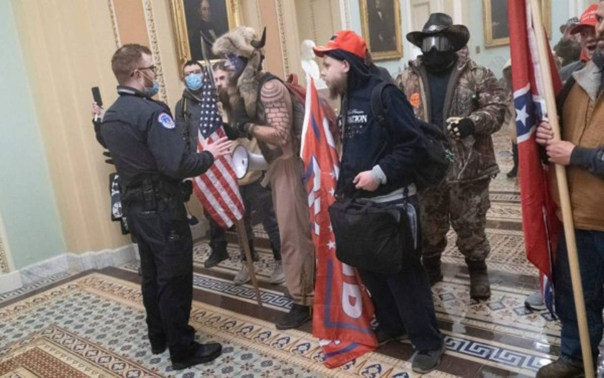 Angeli habla con un policía del Capitolio de EEUU luego de que varios manifestantes irrumpieran en el edificio cuando el Senado debatía los resultados del Colegio Electoral que otorgaron la victoria al candidato presidencial Joe Biden. Fotos AFP