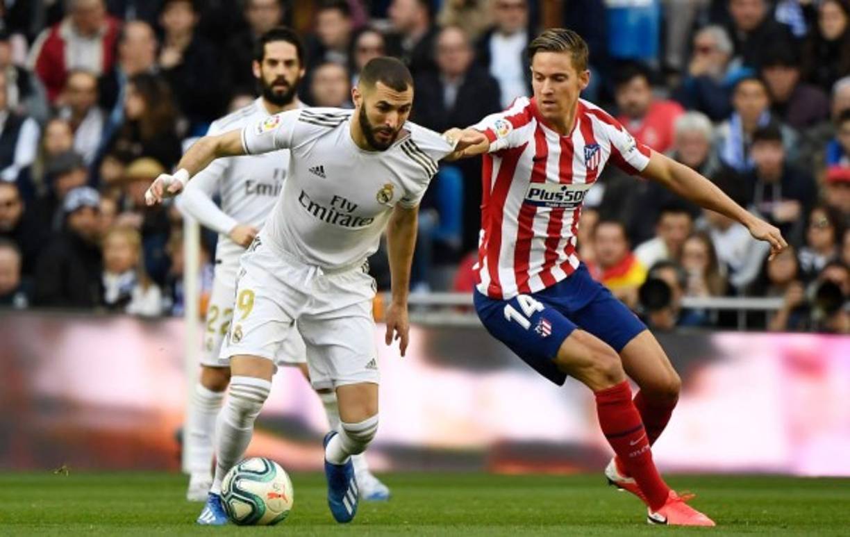 Marcos Llorente sujeta de la camiseta a Karim Benzema que cubre el balón.