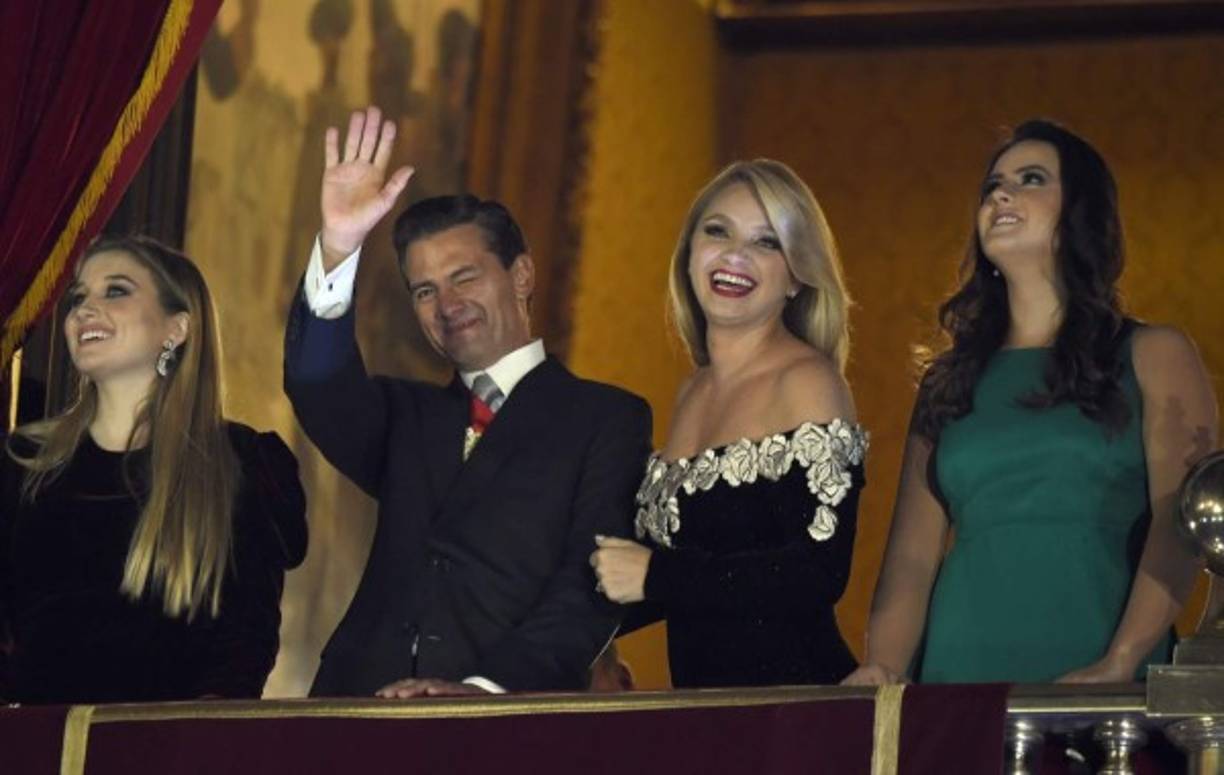 Mexican President Enrique Pena Nieto waves beside his wife and First Lady Angelica Rivera and daughters on the main balcony of the National Palace during ceremonies called 'The Shout' marking the start of celebrations of Independence Day in Mexico City on September 16, 2017. / AFP PHOTO / ALFREDO ESTRELLA