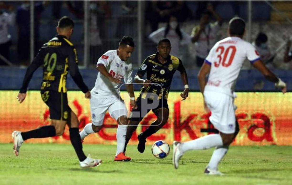 Edwin Rodríguez manejando el balón entre dos jugadores del Real España y ante la mirada de su compañero Eddie Hernández.