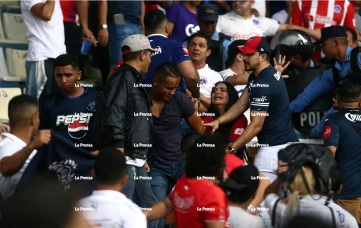 El incidente provocó una pelea en el sector de silla. Una aficionada del Olimpia, entre lágrimas, intenta calmar al hincha que terminó ensangrentado.