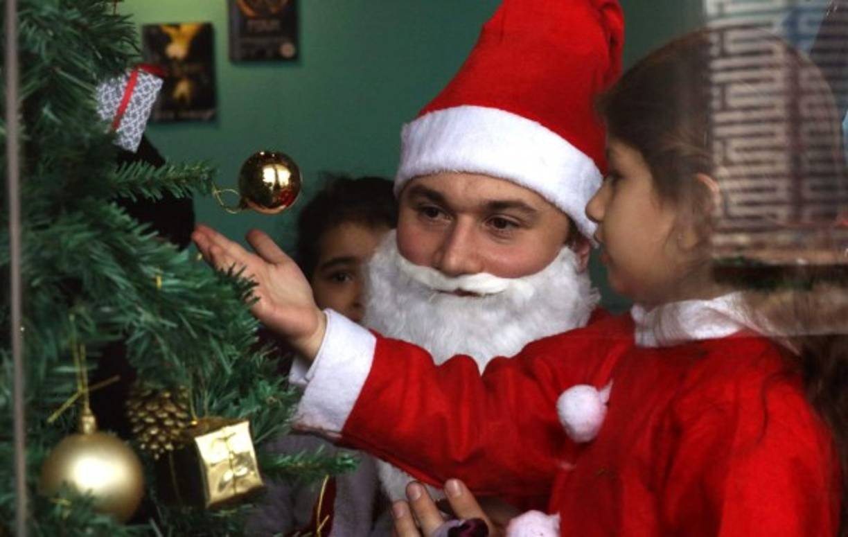 Un hombre vesido de Santa Claus juega con un niño en una provincia de Irak.