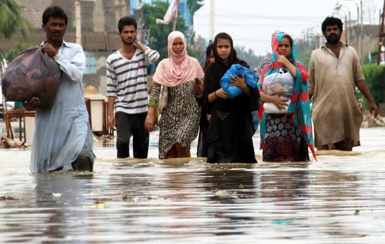 PAKISTÁN. Anegados por la fuerza del monzón. Una familia camina por las calles inundadas del centro de Karachi; al menos 11 personas han perdido la vida en las últimas 24 horas por las lluvias.