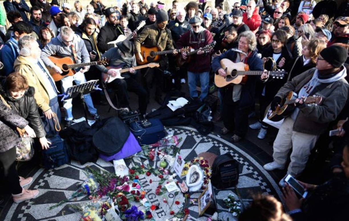 Varias personas se congregan para cantar y observar imágenes del asesinado músico británico John Lennon en el Central Park de Nueva York, en el monumento bautizado como 'Strawberry Fields'.