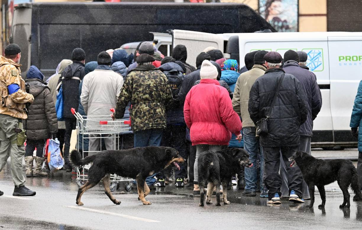 People queue to get aid in town of Bucha, northwest of the Ukrainian capital Kyiv on April 3, 2022. - Britain, France, Germany, the US and NATO all voiced horror at Ukrainian reports on April 2, 2022, of nearly 300 bodies lying in the street in Bucha, with some appearing to have been bound by their hands and feet before being shot. (Photo by Sergei SUPINSKY / AFP)