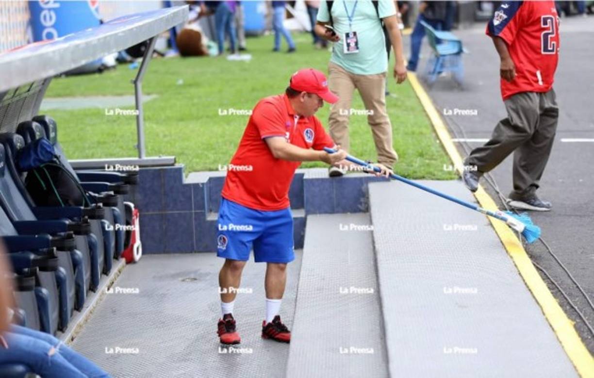 Marvin Martínez, utilero del Olimpia, con escoba en mano hizo una limpia en el banquillo de los albos ya que Diego Vázquez acostumbra a tirar azúcar al lugar del visitante cuando Motagua es local.