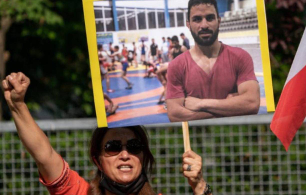 Una simpatizante del Consejo Nacional de la Resistencia Iraní (NWRI) y de la Sociedad del Exilio Iraní en Berlín sostiene una pancarta con la foto del luchador iraní Navid Afkari.