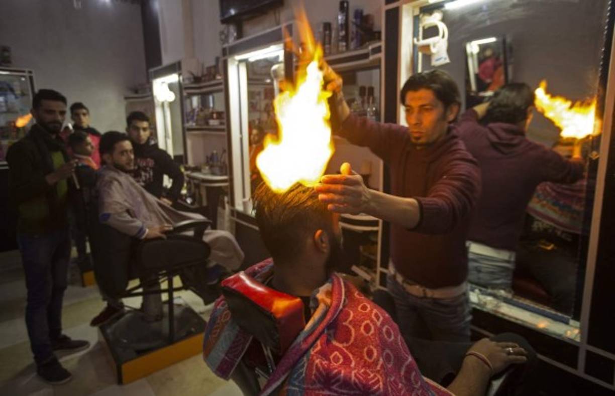 Un peluquero palestino realiza un corte de cabello con una novedosa técnica que utiliza el fuego.