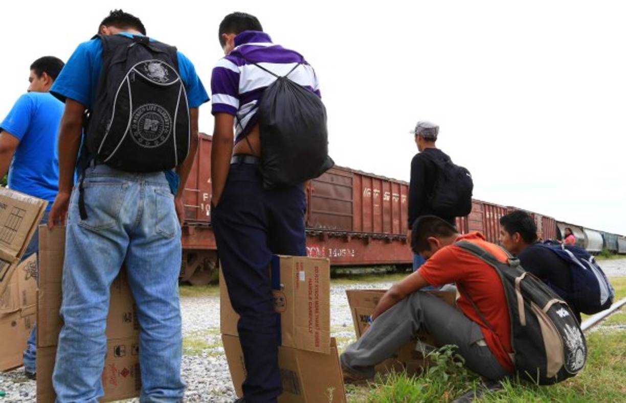 Varios migrantes hondureños sin comida ni transporte esperan subirse a los vagones del tren en México.