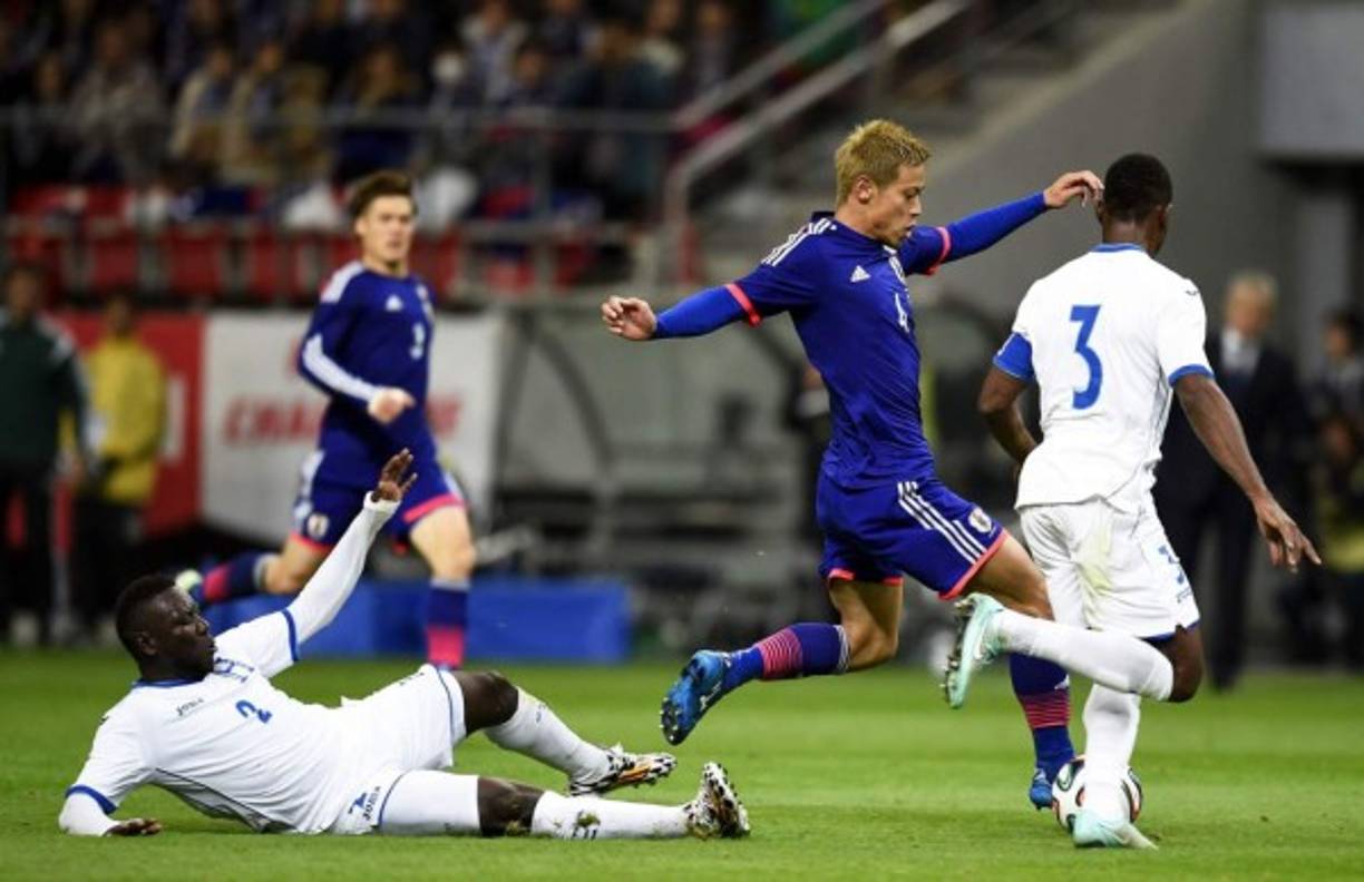 Keisuke Honda intenta pasar de los defensas hondureños Wilmer Crisanto y Maynor Figueroa.