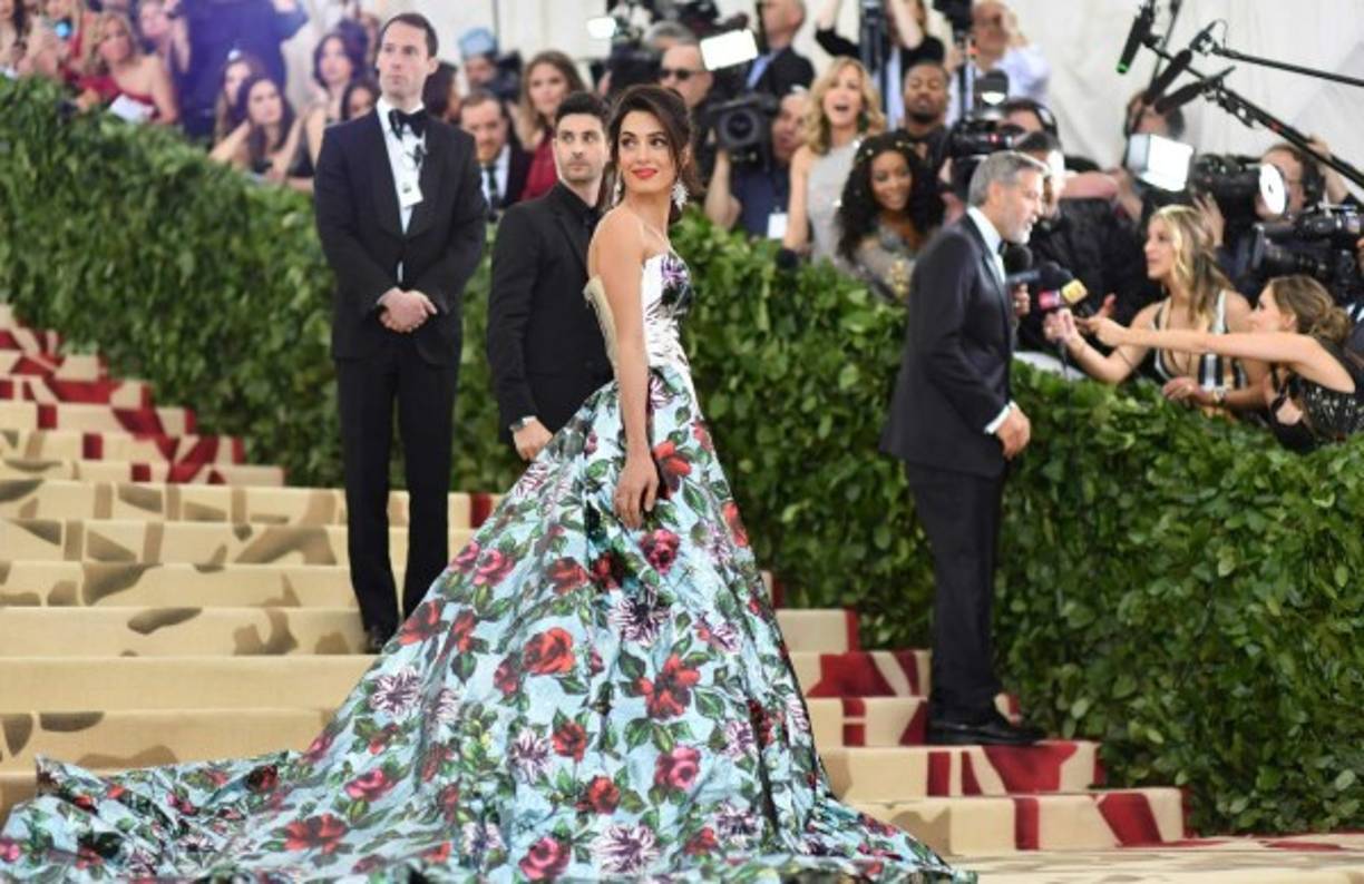 Una de las grandes favoritas de la noche fue Amal Clooney, abogada libanesa y esposa de George Clooney, quien lució un vestido pantalón con una impactante cola redonda en un celeste grisáceo satinado con flores rojas estampadas.