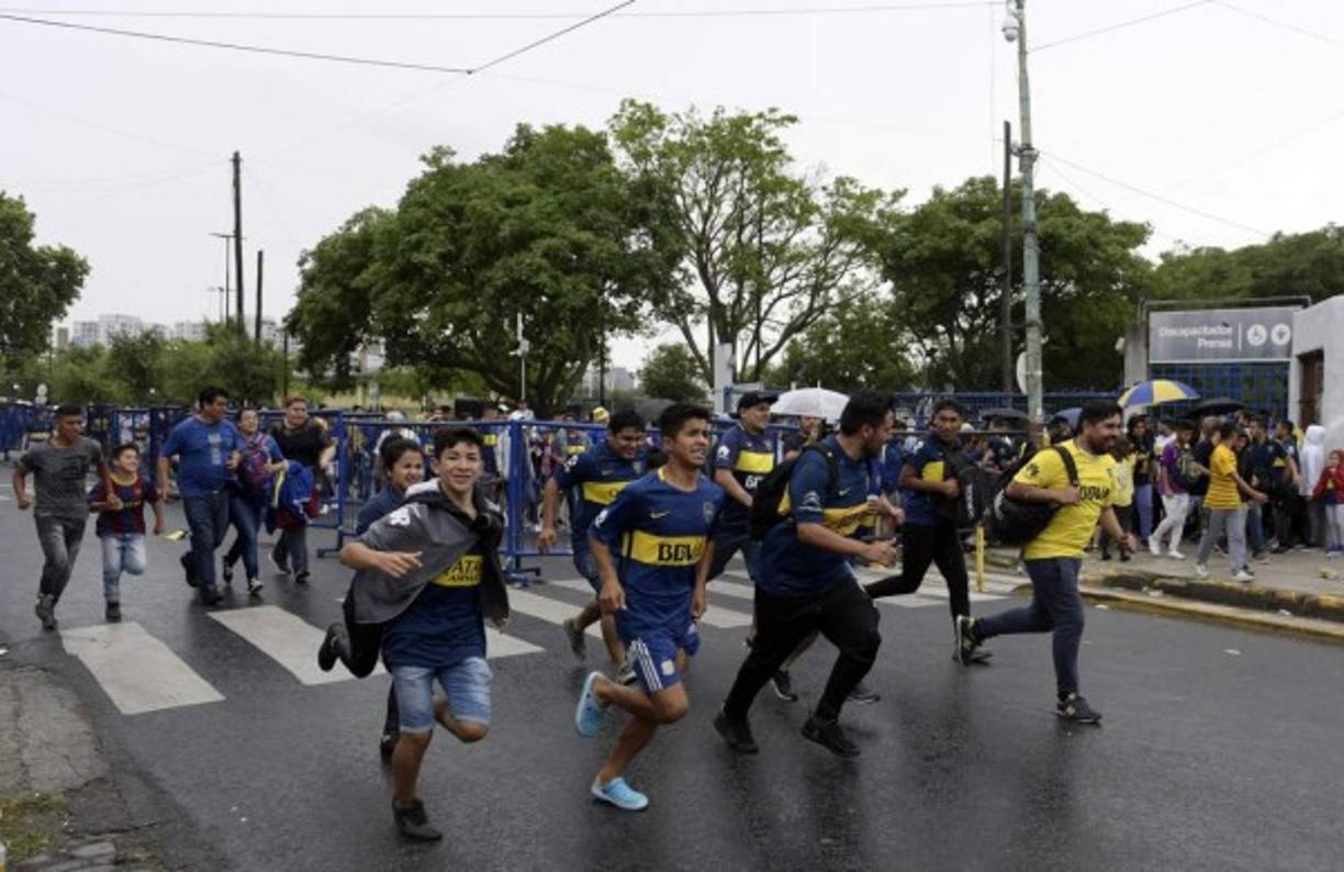 Los aficionados de Boca Juniors corren para ingresar a La Bombonera y observa el entrenamiento de este jueves.