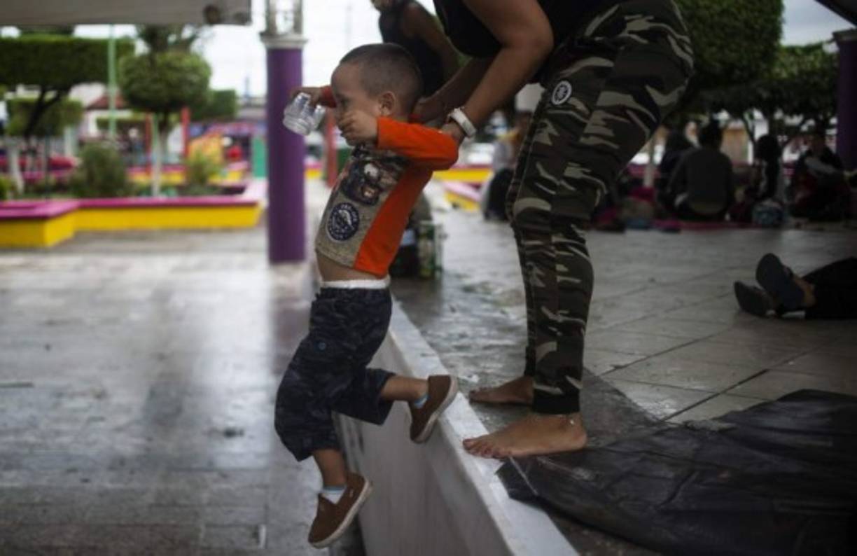 Una mujer ayuda a un niño a bajar al nivel del suelo, ya en territorio mexicano.