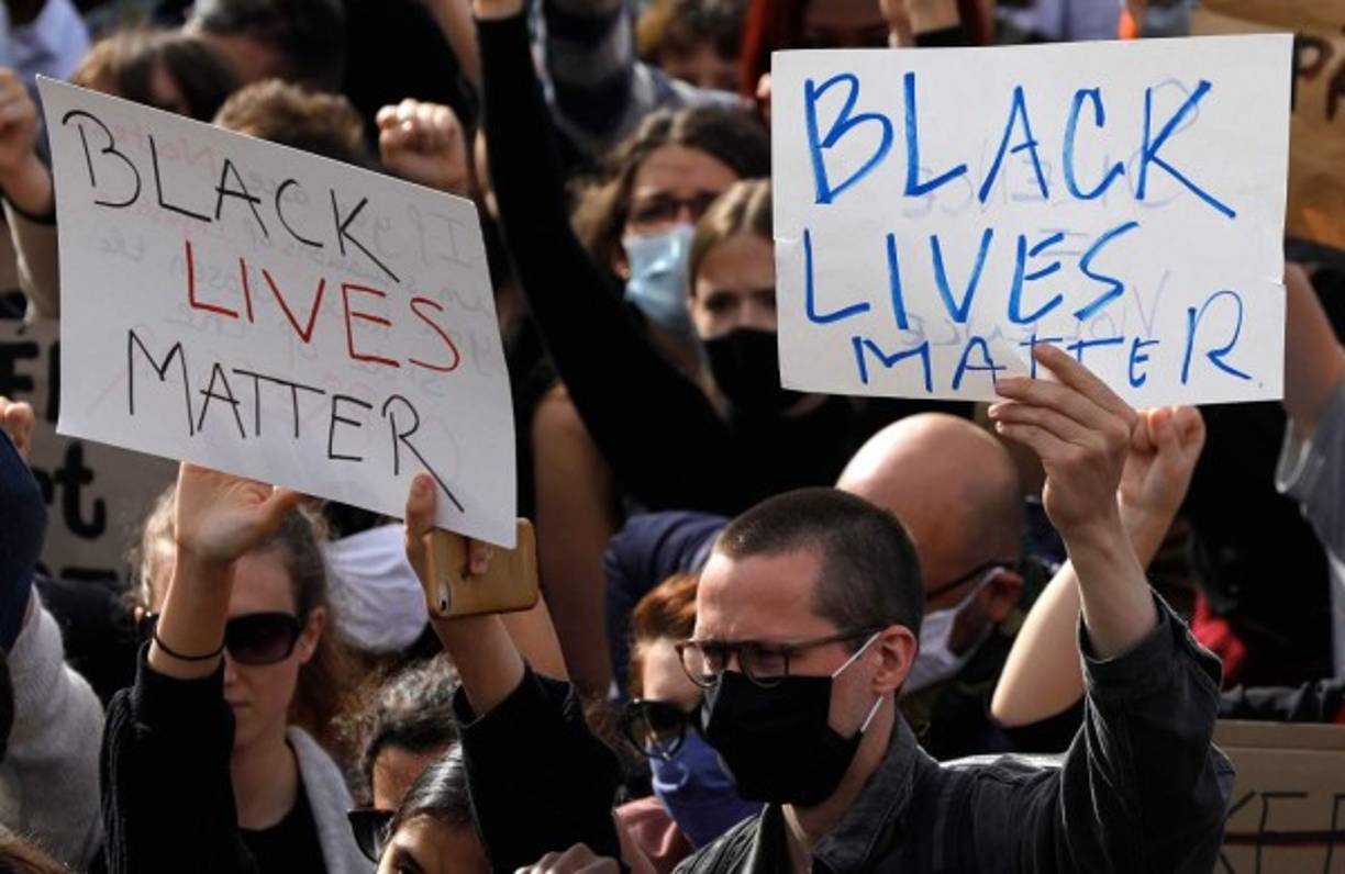 Las personas sostienen carteles mientras se reúnen en Champ de Mars frente a la Torre Eiffel, en París. AFP