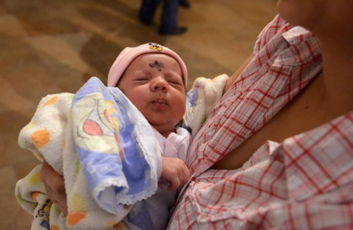 Una mujer católica sostiene a su bebé mientras ella asiste a misa para celebrar el Miércoles de Ceniza, que marca el inicio de la Cuaresma. AFP