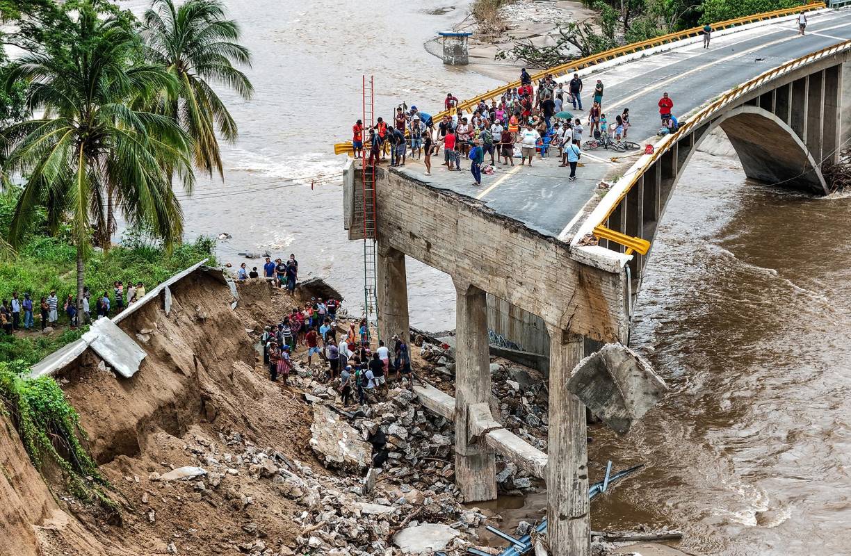 Damnificados tratan de cruzar por un puente destruido como consecuencia del paso del huracán John por Acapulco, México, el 30 de septiembre. 