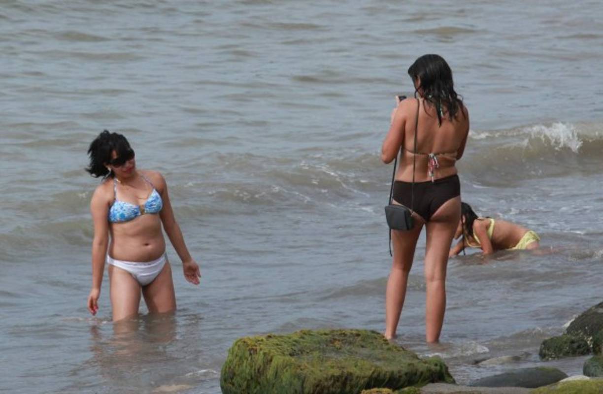 Una mujer toma una foto a su compañera de viaje en la ciudad de Tela, Atlántida.