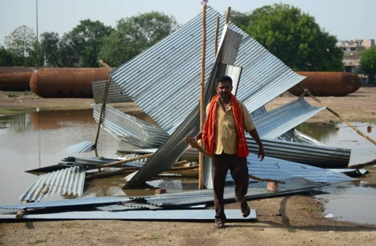 An Indian man passes next to a destroyed tin shed near a construction site following a major storm in Allahabad on May 3, 2018.<br/>Powerful dust storms tore across northern India killing at least 100 people and injuring more than 140 as they flattened houses in their path and warnings were made May 3 of more chaos to come. / AFP PHOTO / SANJAY KANOJIA