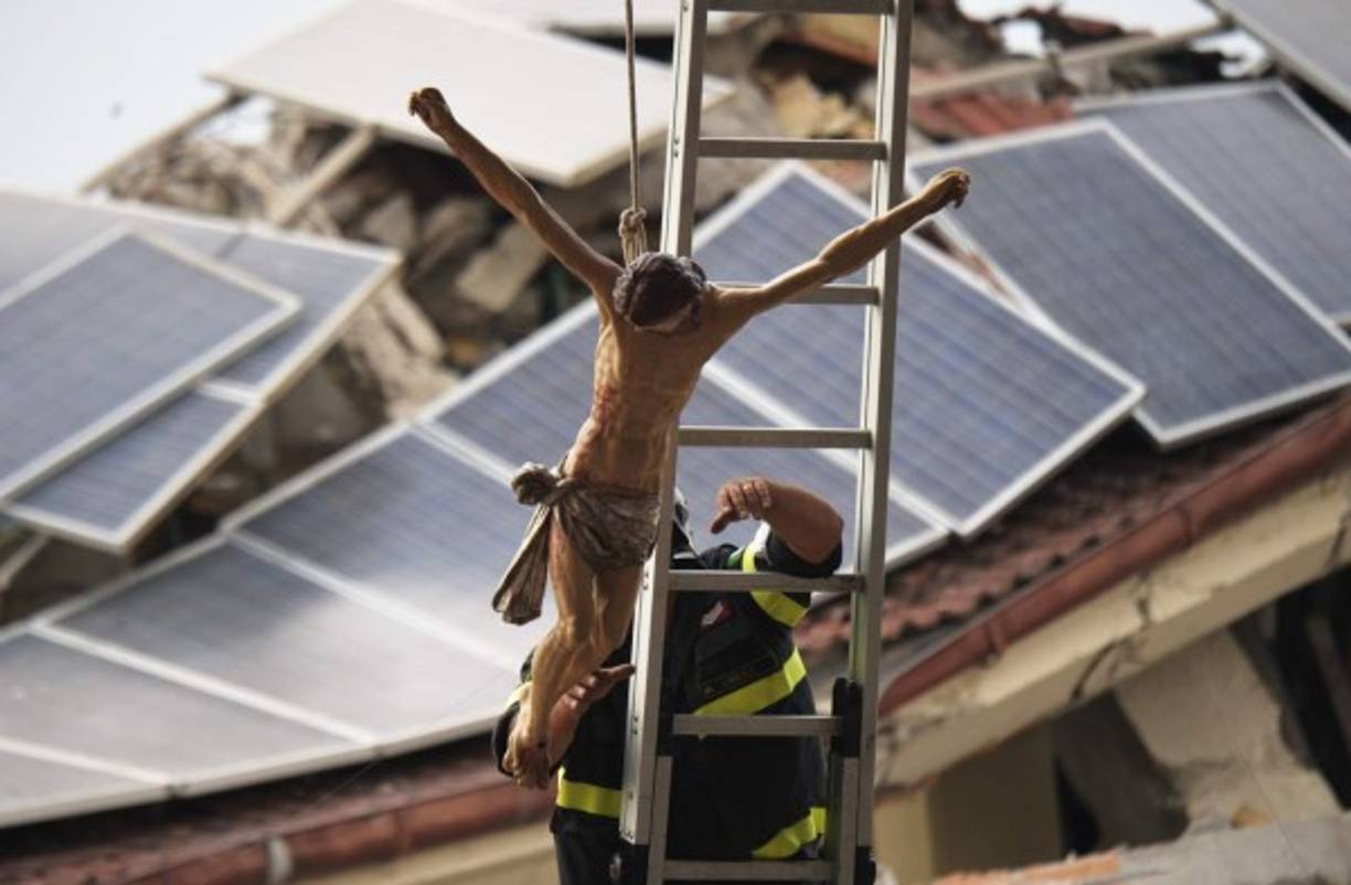 ITALIA. Dolor entre las ruinas. Un bombero fija un crucifijo en Amatrice, antes de la ceremonia del funeral por las víctimas del sismo.