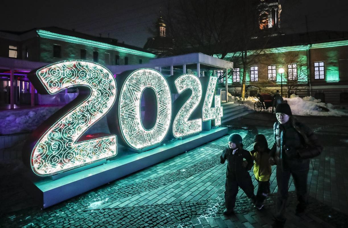  Una mujer camina con sus hijos junto a una instalación de iluminación ‘2024’ durante la inauguración del festival de Año Nuevo y Navidad ‘Moscow Estates. Winter’ en Moscú, Rusia.